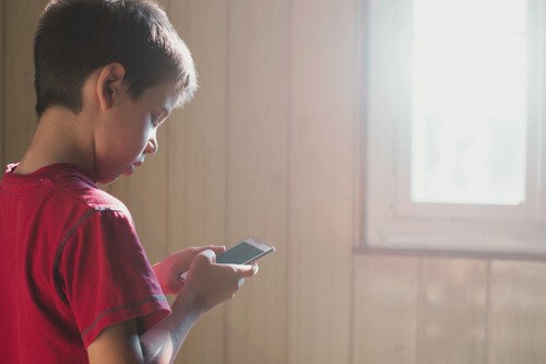 Alerta en el Norte: 4 de cada 10 adolescentes son víctimas de acoso digital Niño utilizando un celular con precaución ante riesgos de internet.
